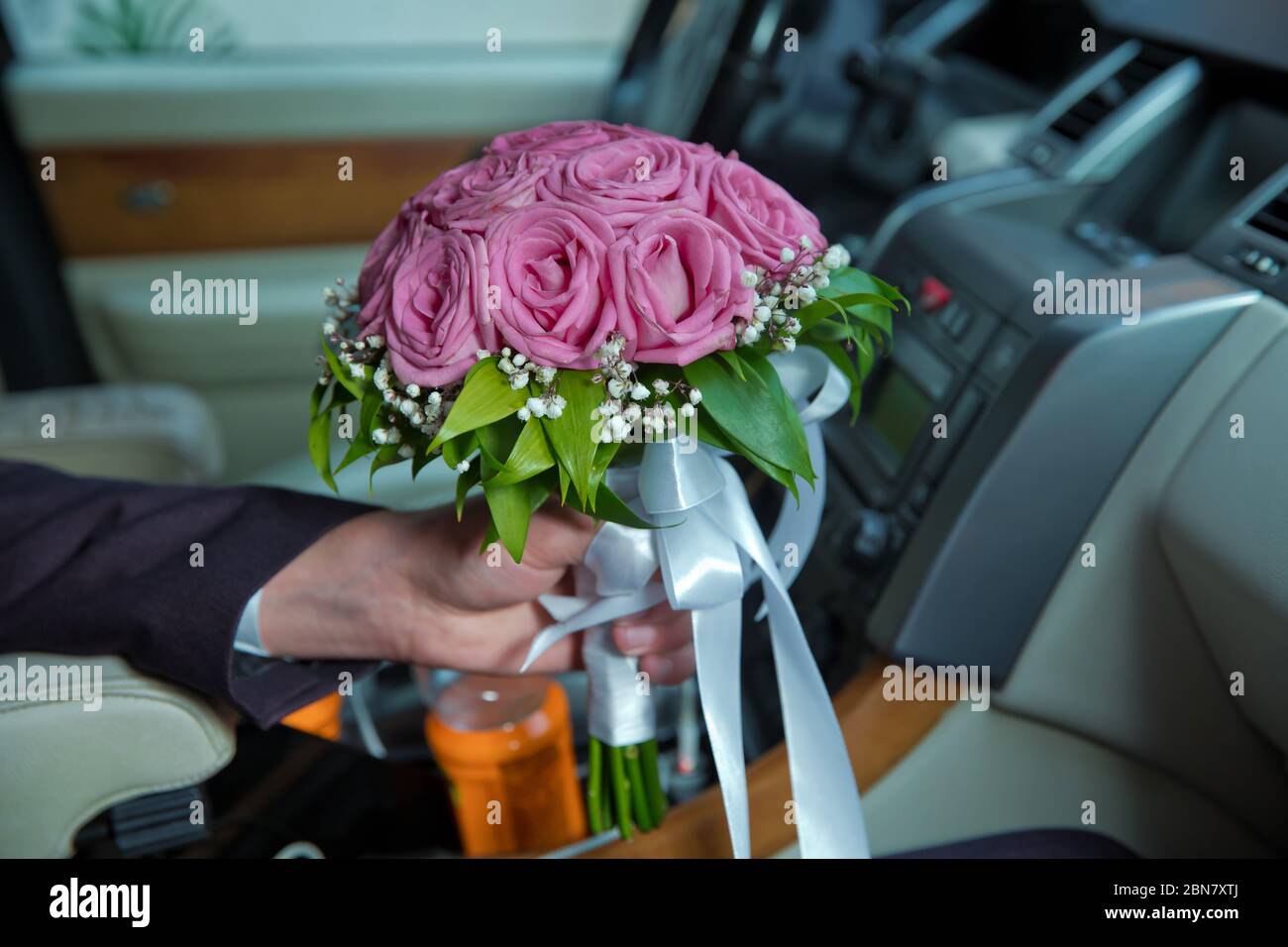 Frau mit Verlobungsblumen, rosa Rosen im Auto. Der Bräutigam hielt einen  Strauß rosa Blumen im Auto Stockfotografie - Alamy