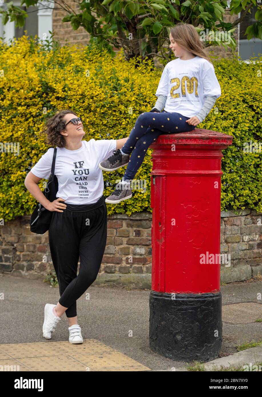 Fiona und ihre Tochter Lola aus London tragen T-Shirts mit dem Slogan: „Wenn Sie dies lesen können, sind Sie zu nahe an COVID“, die vom globalen Unternehmen für die Markenumwandlung FutureBrand als gemeinnützige Initiative ins Leben gerufen wurden, um die wichtigsten Richtlinien für soziale Distanzierung zu stärken, während die Nation aus der Sperrung der Coronavirus-Pandemie herauskommt. Stockfoto