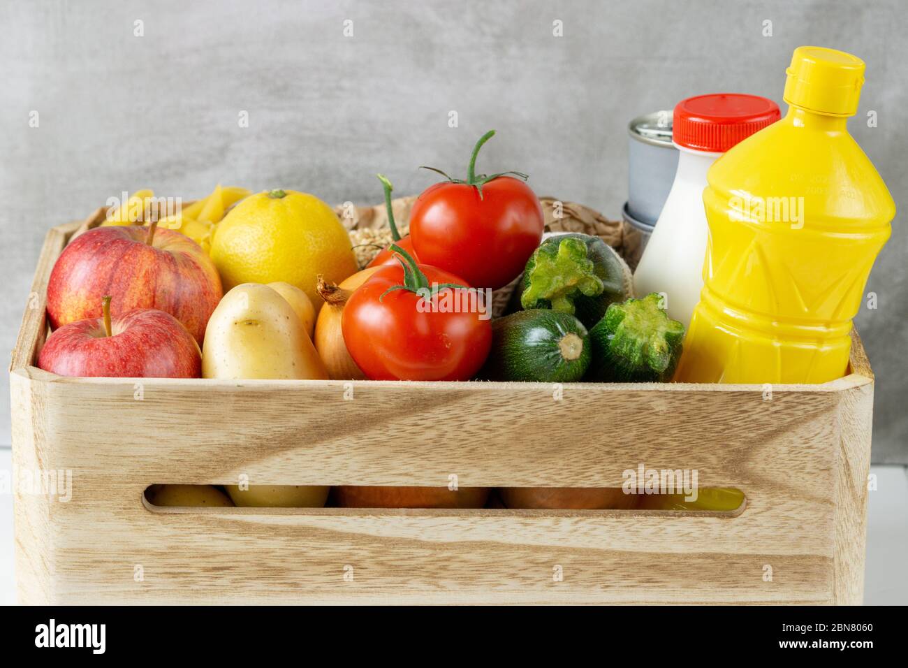 Lebensmittelspende Holzkiste mit Gemüse, Obst, Pasta, Öl, Milch und Konserven. Kopierbereich, Nahaufnahme. Stockfoto