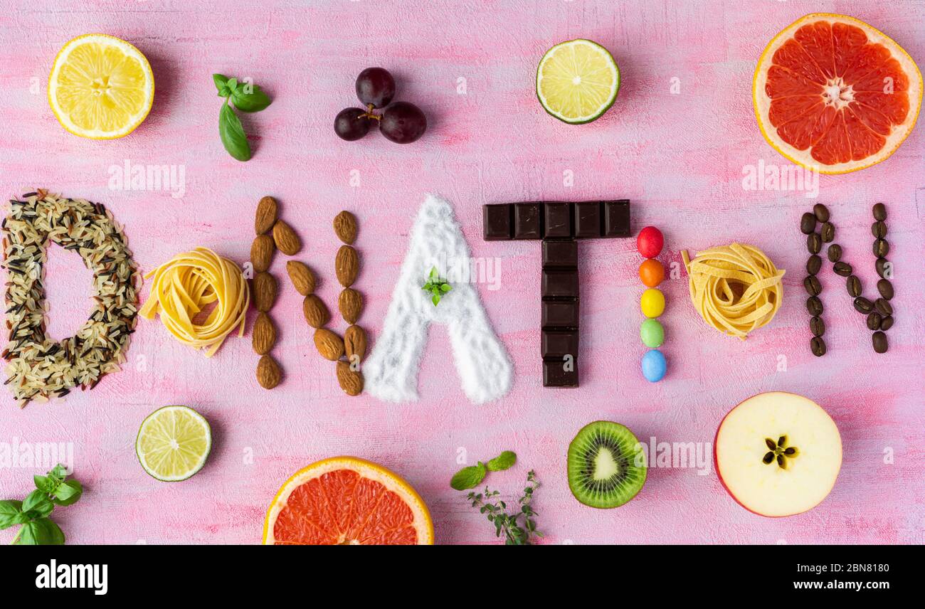 Das Wort Spende aus verschiedenen Arten von Grütze, Nüsse, Schokolade, Kaffee, Zucker und Pasta. Es gibt einige Früchte auf rosa Hintergrund. Draufsicht. Stockfoto