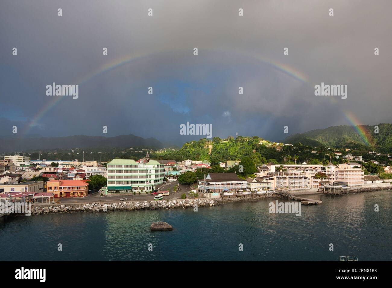 Rouseau, auf der Insel Dominica vom Meer mit einem vollen Regenbogen über der Stadt. Karibik, Westindien. Stockfoto
