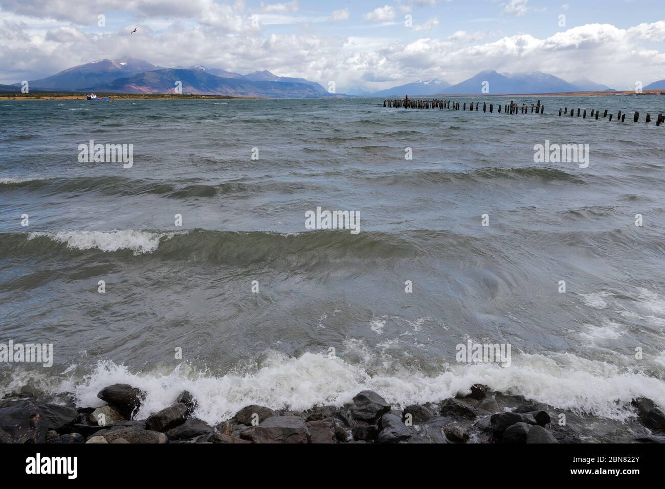 Holzpfosten von einem alten Pier, Puerto Natales, Patagonien, Chile, Cerro Monumento Moore im Hintergrund. Stockfoto