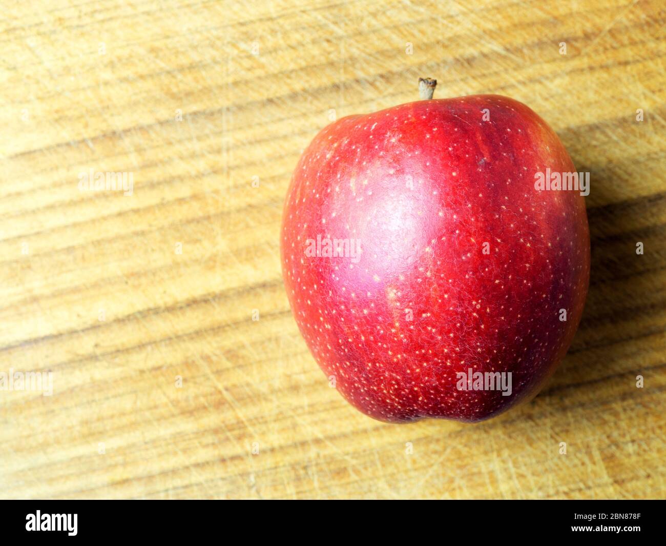 Ein einzelner braeburn Apfel auf einem Holzhackbrett mit Kopierraum Stockfoto