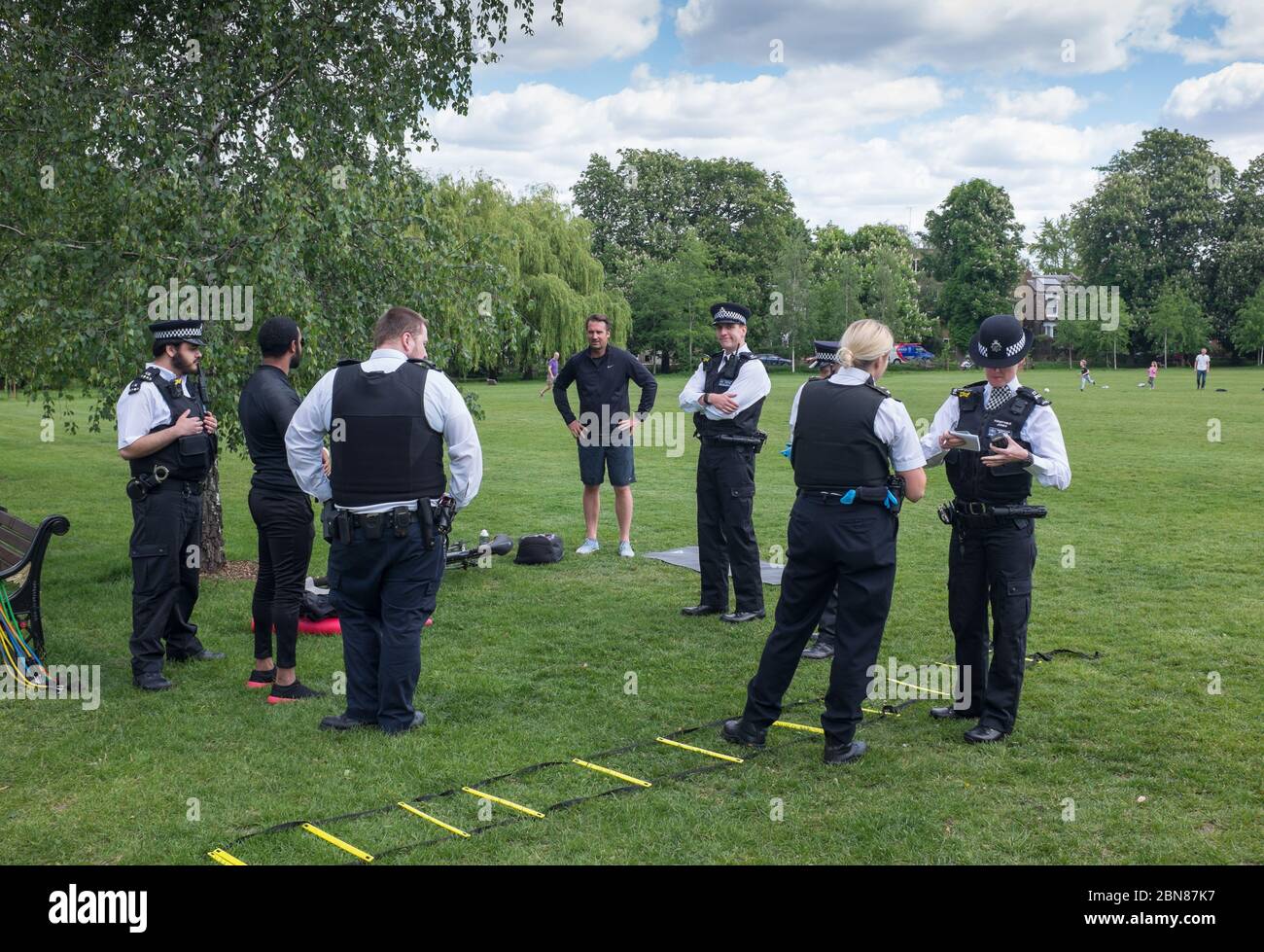 Polizeibeamte auf Patrouille in Stoke Newington sprechen mit zwei jungen Männern, die während der Sperrung des Coronavirus/Covid-19 in einem Park im Norden Londons trainieren Stockfoto
