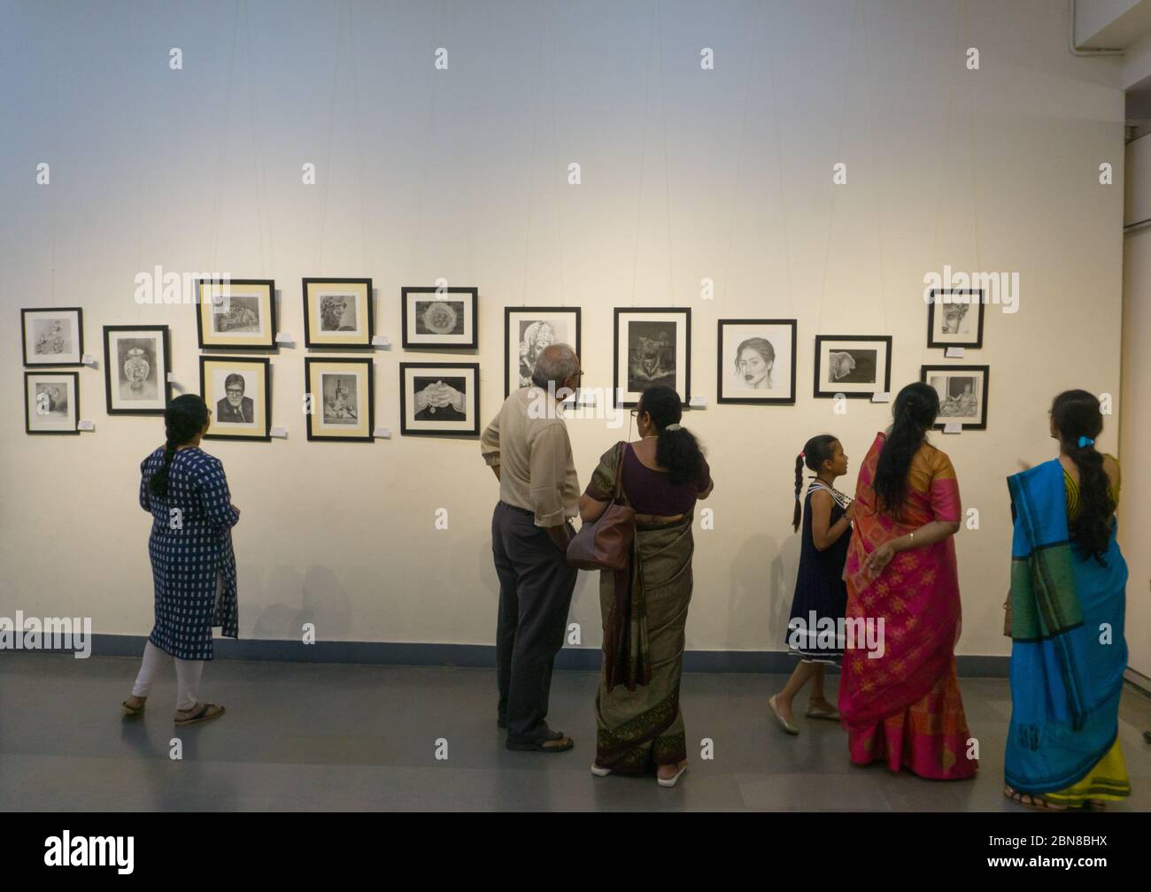 Menschen, die die in einer Ausstellung in Chitrakala Parishath in Bangalore (Indien) ausgestellten Gemälde sehen Stockfoto