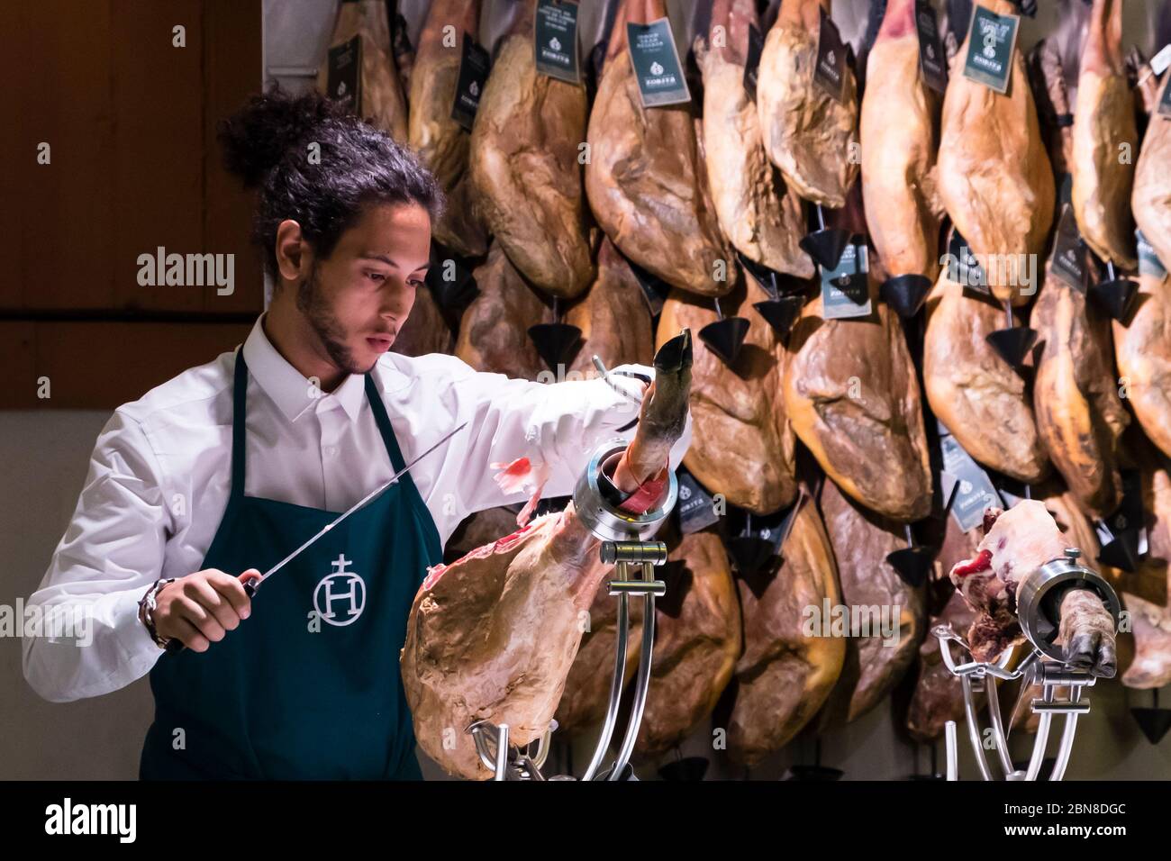 Ein männlicher Ladenarbeiter schneidet gekonnt iberischen Schinken in Viandas, Leadenhall Market, London, Großbritannien Stockfoto