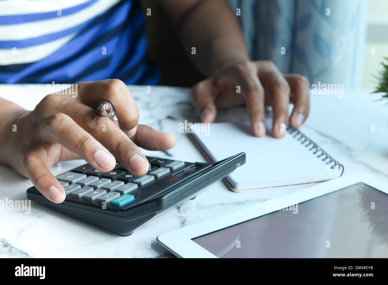 Junger Mann verwenden Rechner und Schreiben auf Notizblock im Home Office. Stockfoto