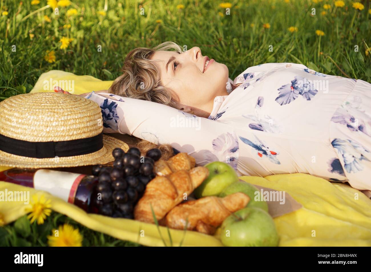 Junges Mädchen, das mit Wein und frischem Essen auf dem Karaid liegt. Picknick. Tageslicht Stockfoto