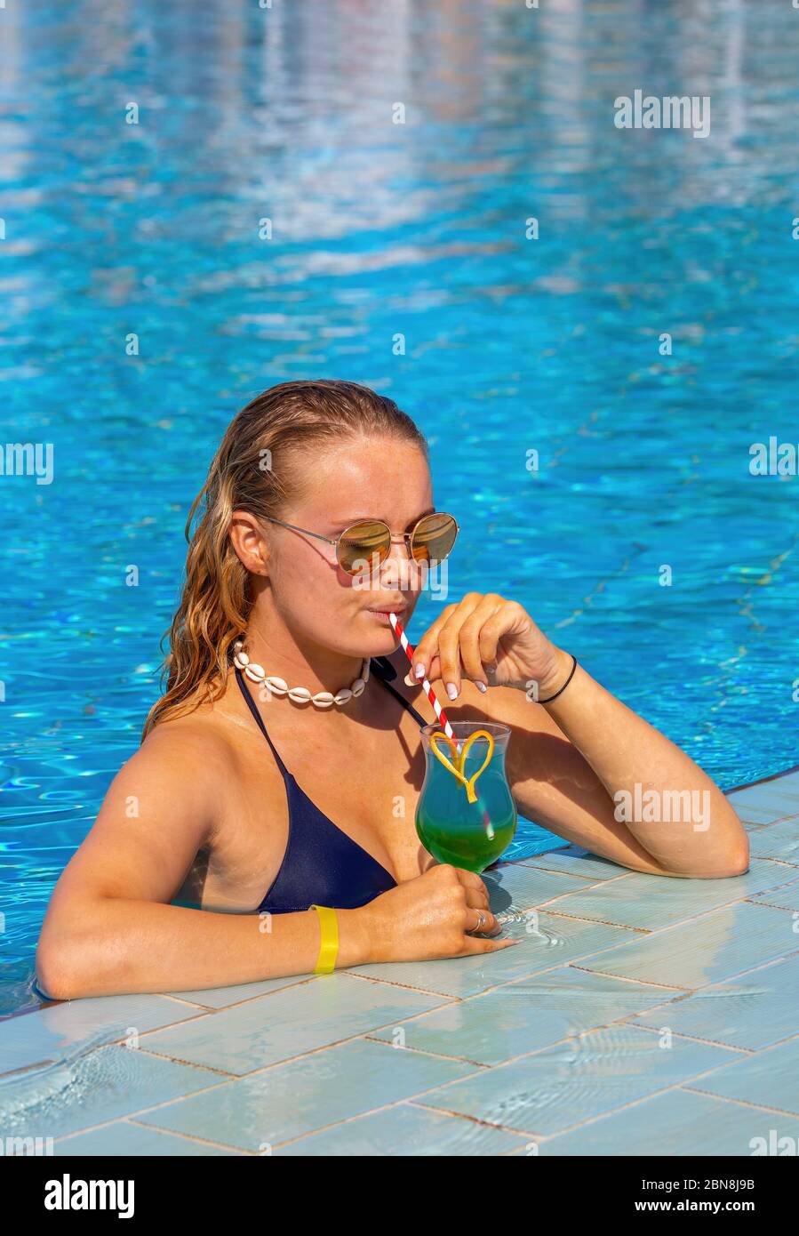 Junge kaukasische Frau trinkt Cocktail-Drink im Schwimmbad Stockfoto