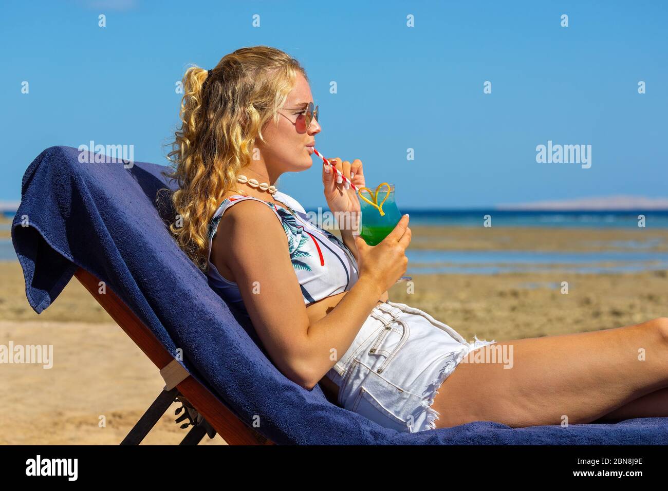 Junge holländerin am Strandbett trinkt alkoholischen Cocktail Stockfoto