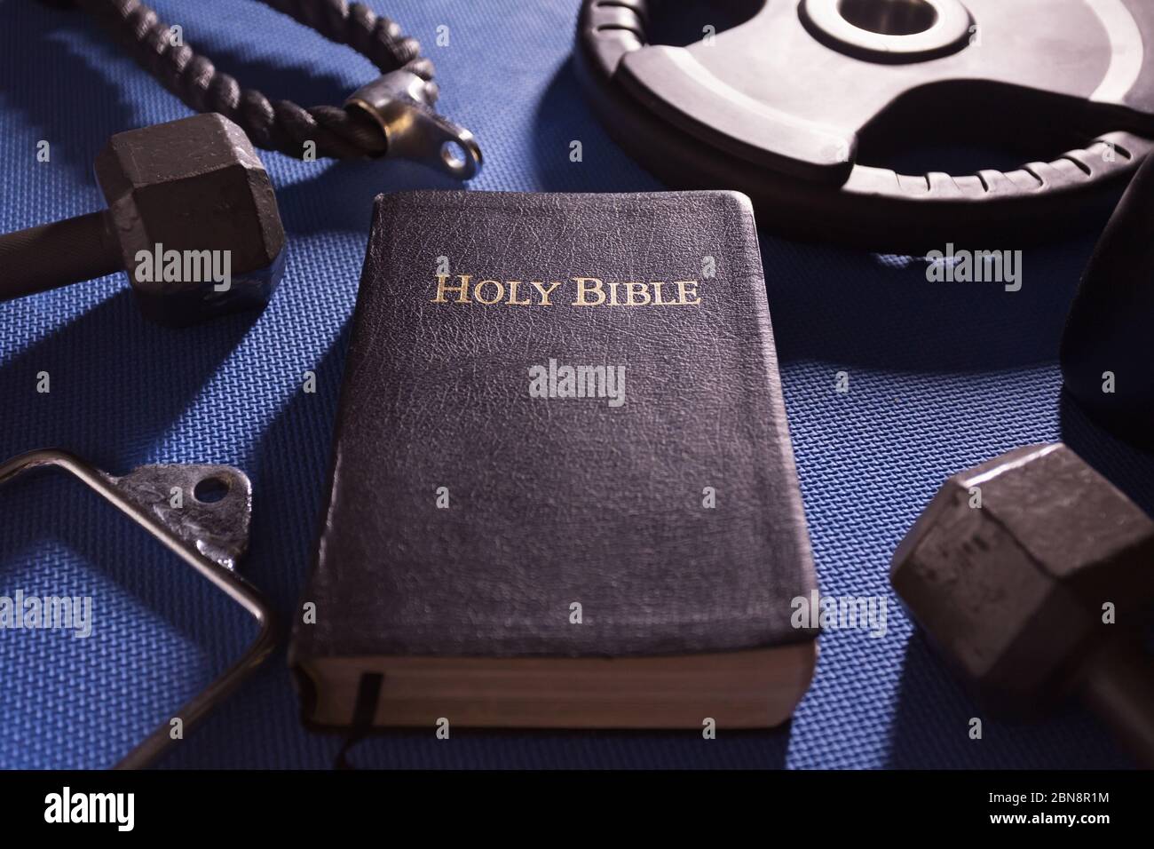 Heilige Bibel umgeben von Hanteln Gewichte und andere Trainingsgeräte Stockfoto