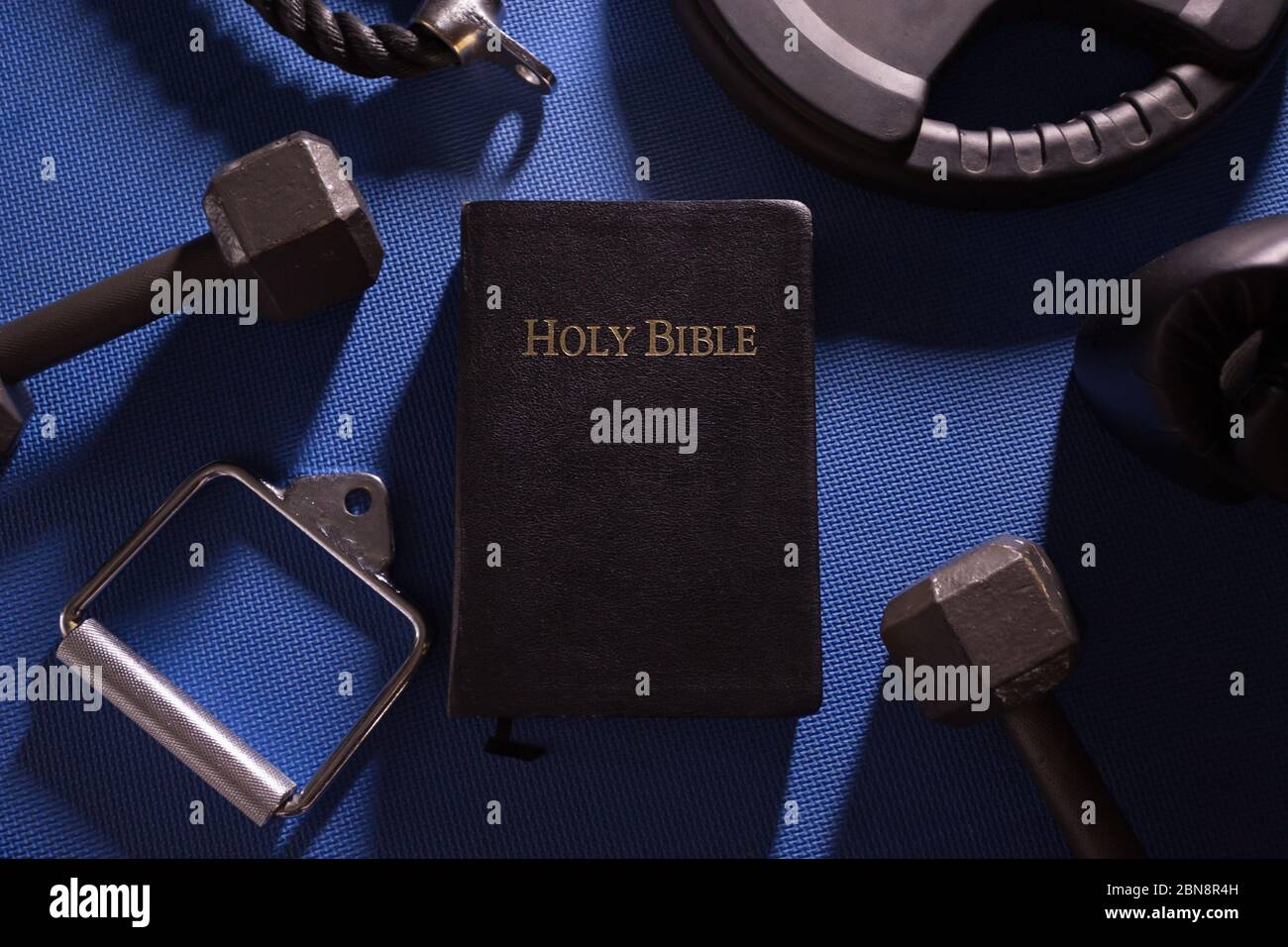 Heilige Bibel umgeben von Hanteln Gewichte und andere Trainingsgeräte Stockfoto