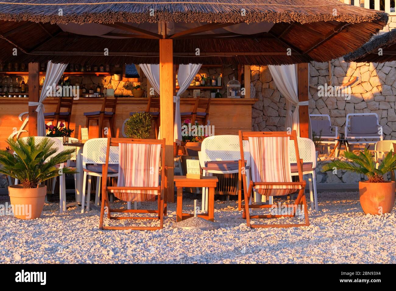 Café an der Küste mit Stühlen, Tischen und Sonnenliegen. Urlaub, Tourismus und Resort im sonnigen Sommer. Stockfoto