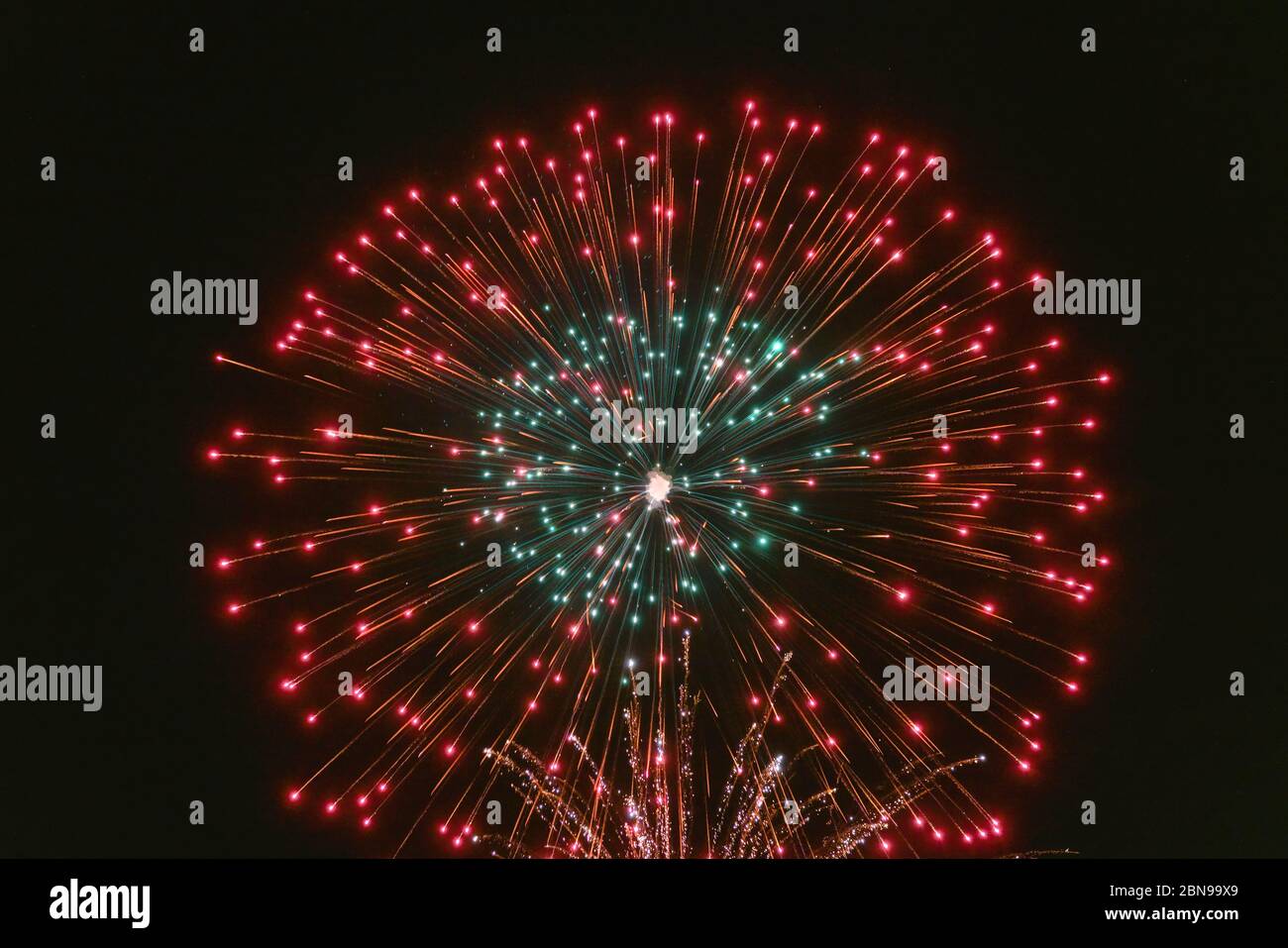 Rotes und grünes Feuerwerk mit Rauch über dem schwarzen Himmel. Geringe Tastenbelichtung. Stockfoto