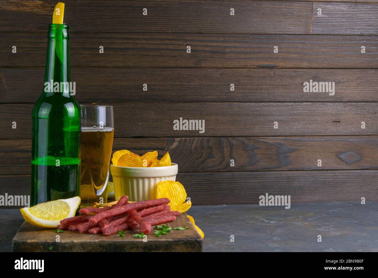 Trockene Lachssticks mit Bier, Zitrone und Kartoffelchips auf dunklem ...