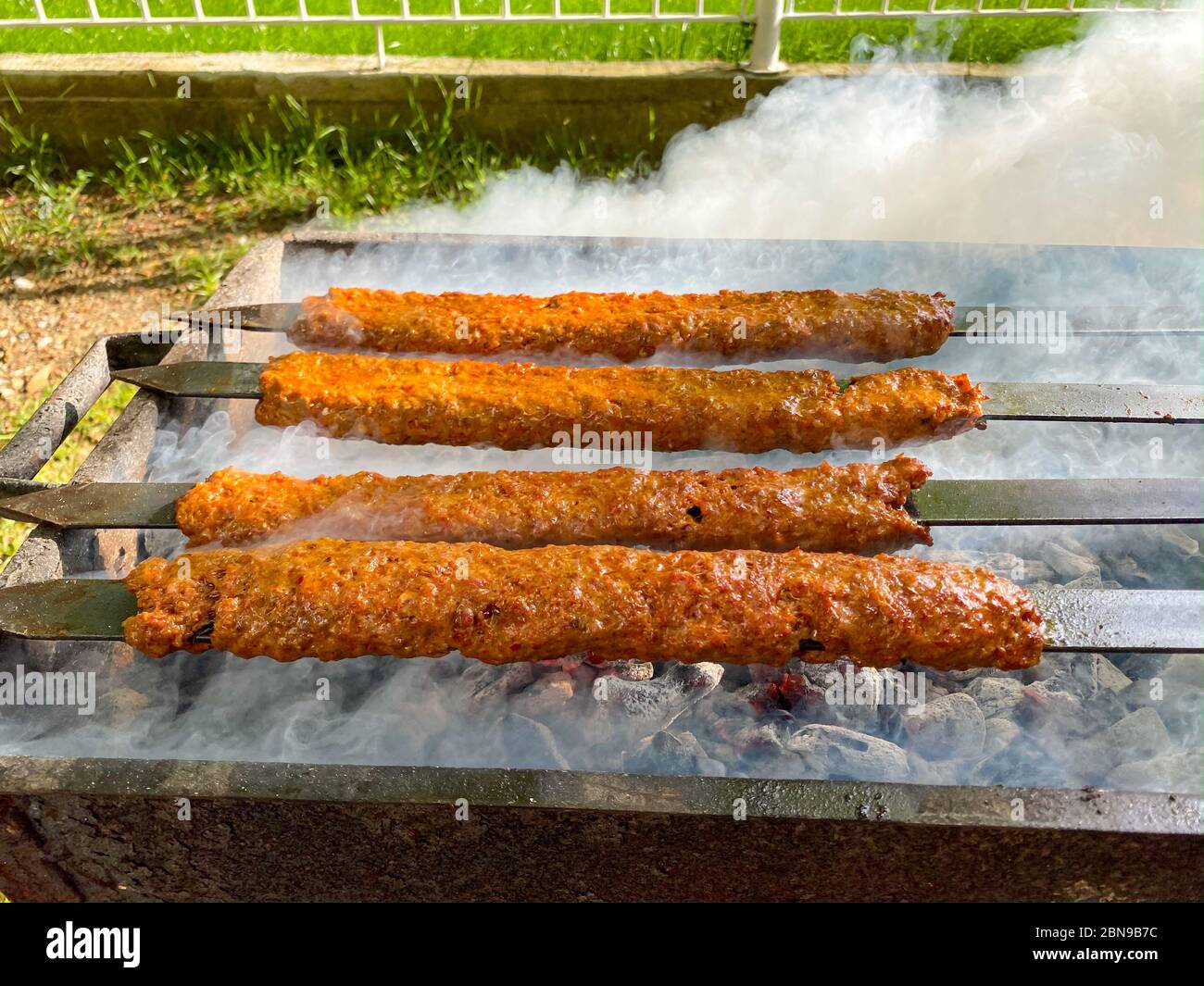 Traditionelles türkisches Adana Kebap auf dem Grill mit Spiessen zum Abendessen. Türkische Küche Esskultur in der Türkei. Adana Kebab auf dem mangal in der Natur. P Stockfoto
