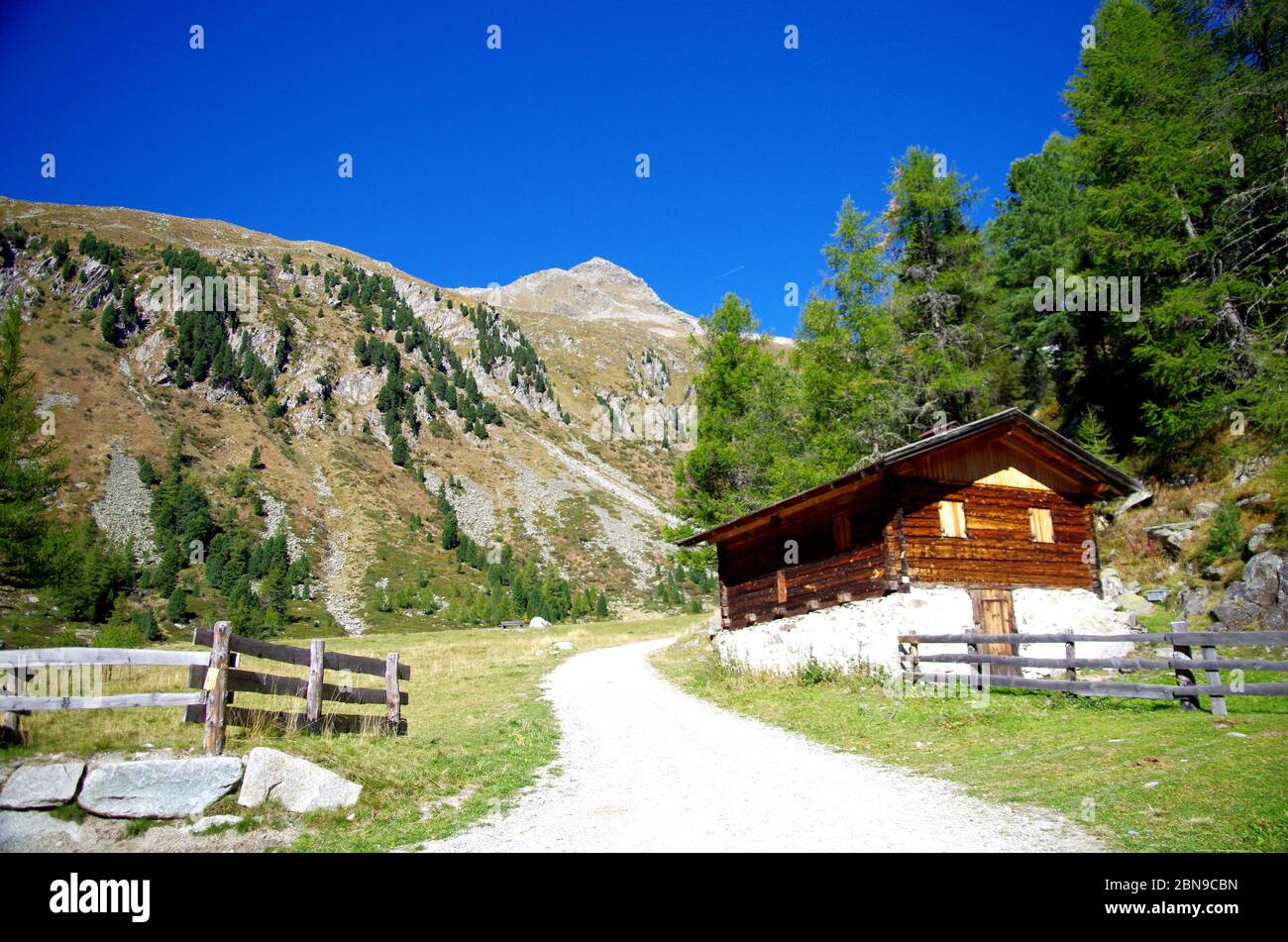 Hoher Berg mit grünen Wiesen und üppigen Wäldern und scharfen Felsen und typische Haus, Blockhaus, in Holz und Stein unter dem blauen Himmel Stockfoto
