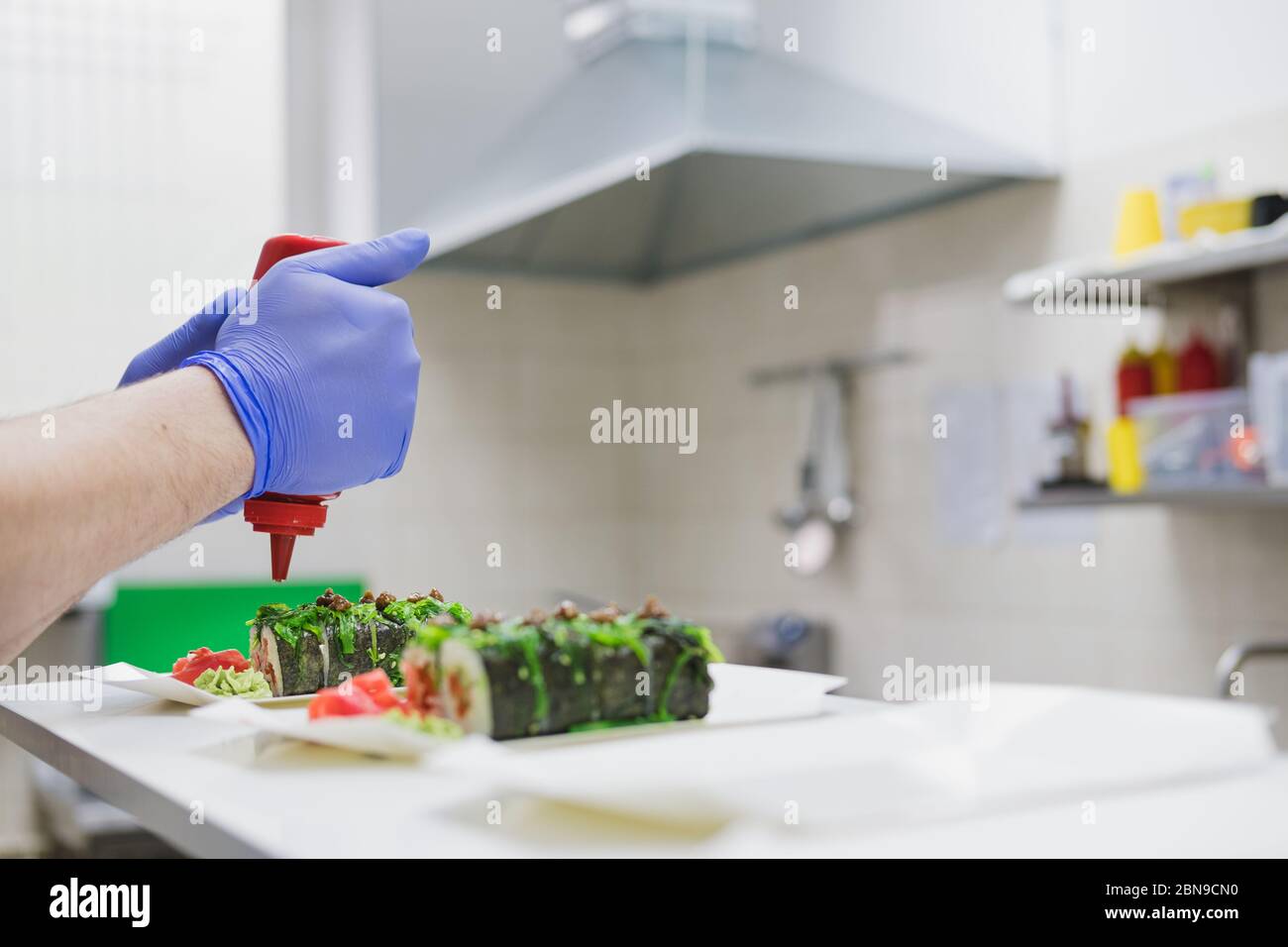 Die Hände eines Küchenchefs bereiten ein Sushi-Brötchen zu. Fast-Food-Küche, asiatische Lebensmittel, Essen zum Mitnehmen Zubereitung Stockfoto