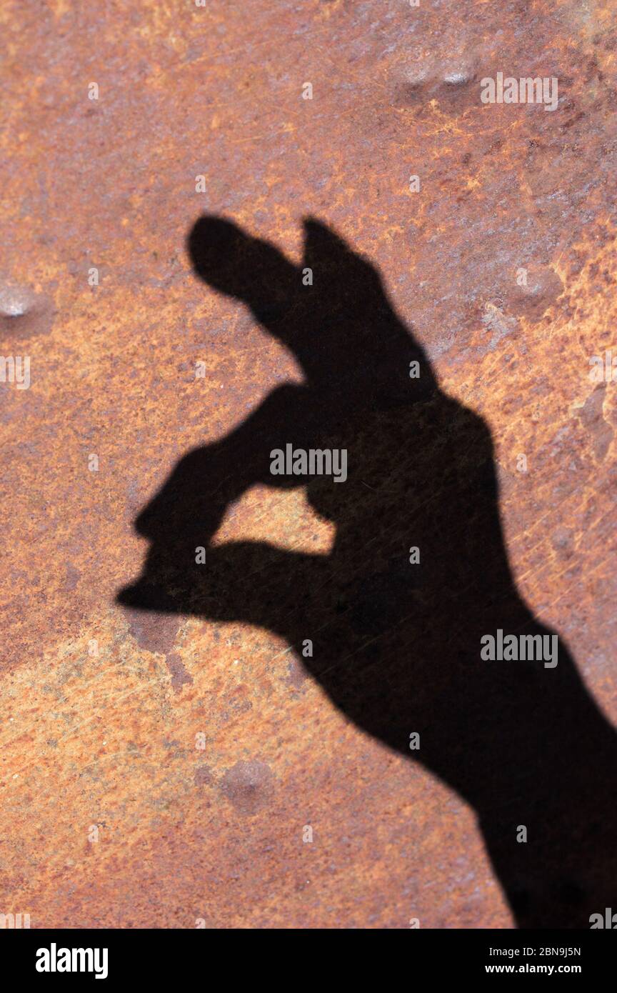 Der Schatten einer Hand bildet den Kopf eines Kaninchens an einer braunen Wand Stockfoto