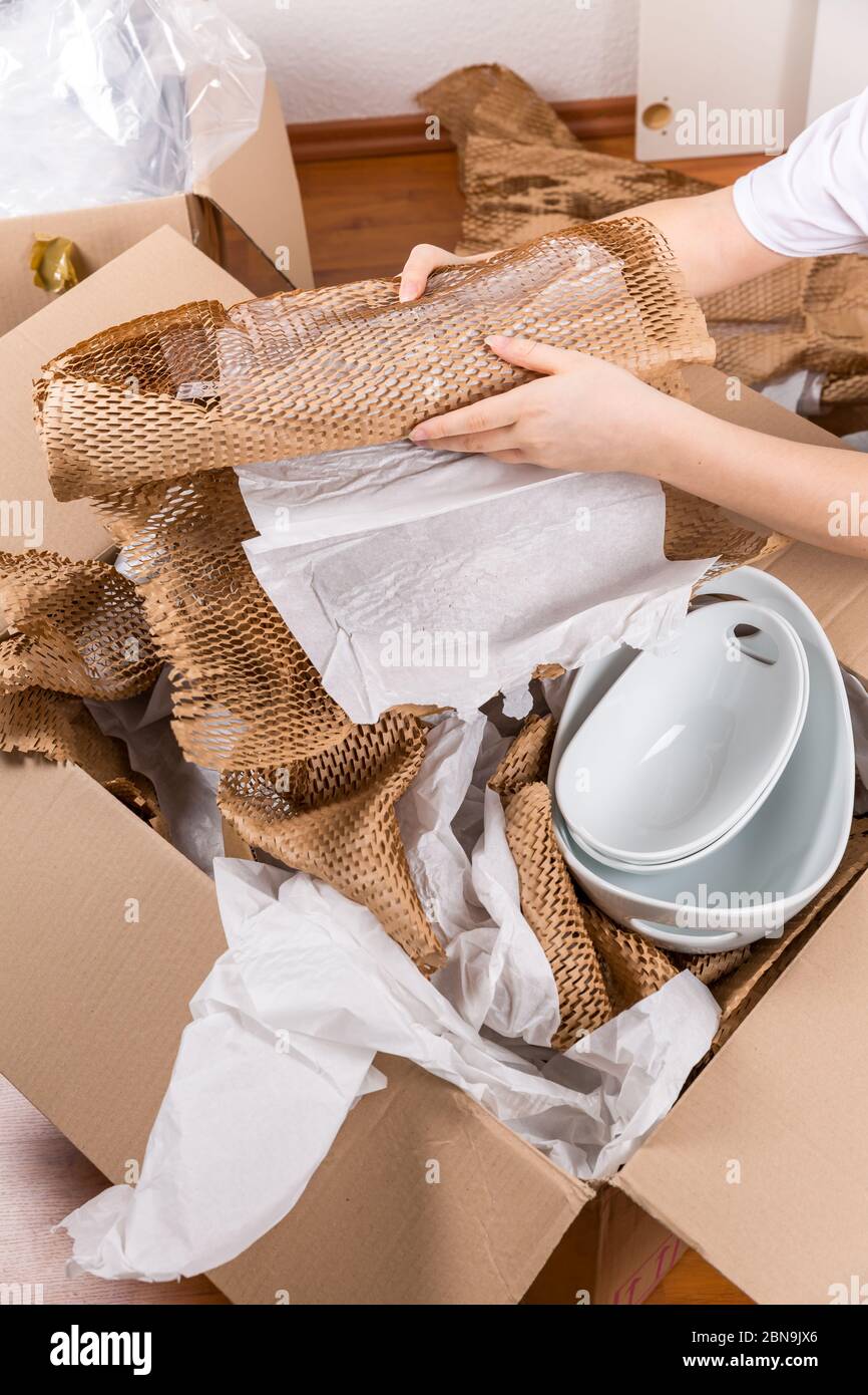 Detail der Frau Verpackung zerbrechlichen Artikel mit zerknittert Verpackungspapier. Konzept des ein- und Ausfahrens. Stockfoto