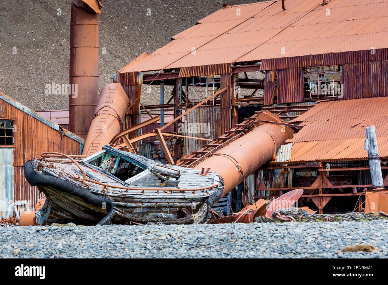 Altes Holzboot ruht am Ufer vor Rostiger Metallbau auf Stomness Island Stockfoto