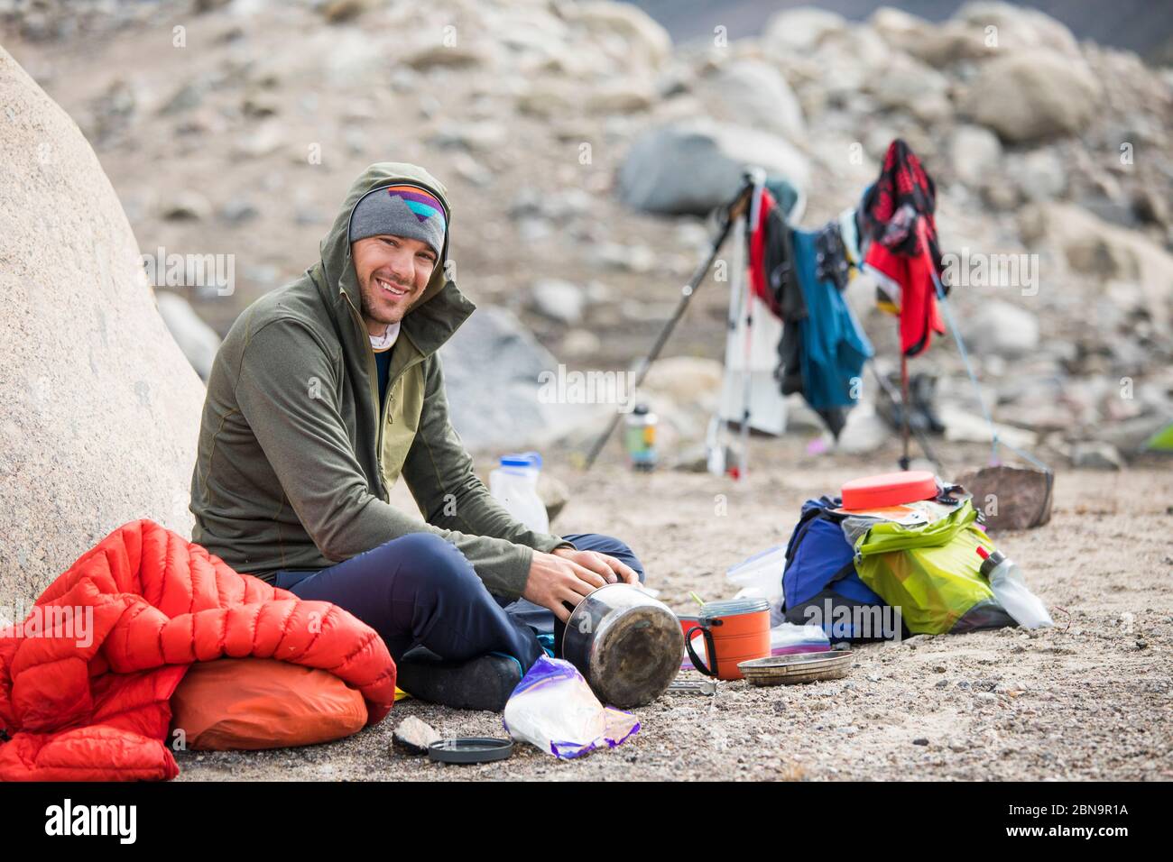Portrait eines Bergsteigers, der sich für eine Mahlzeit im Lager hinsetzte. Stockfoto