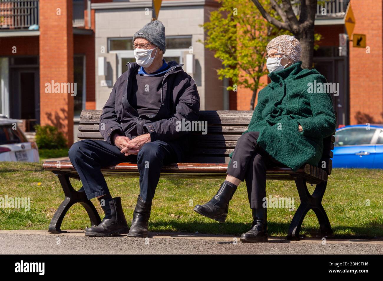 Montreal, CA - 13. Mai 2020: Ältere Männer und Frauen mit Gesichtsmasken auf einer Bank in einem Park, während der Covid-19-Pandemie Stockfoto