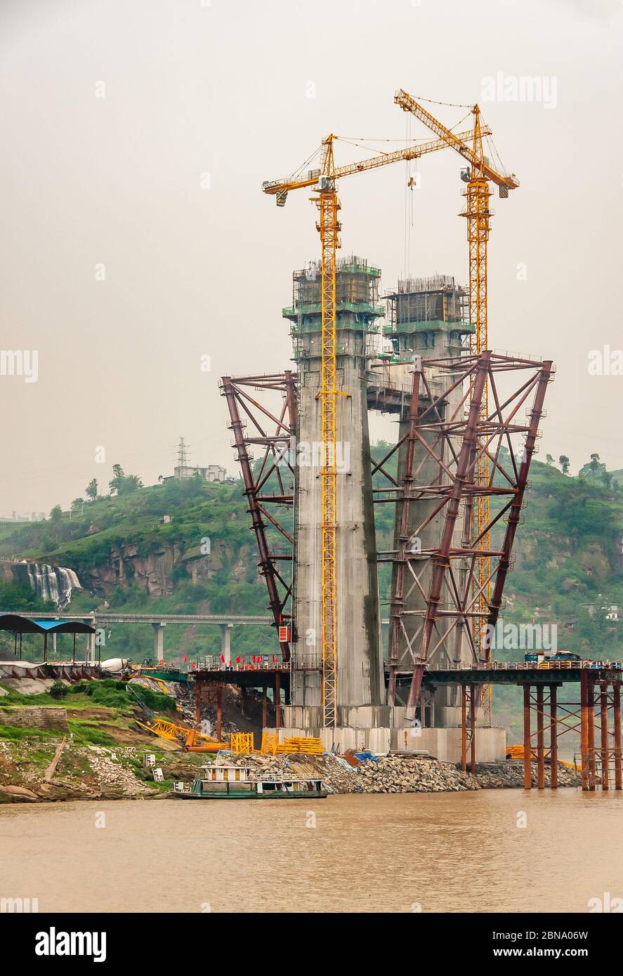 Fengdu, Chongqing, China - 8. Mai 2010: Jangtze River. Nahaufnahme von Beton Hängeturm für Brücke im Bau mit 2 hohen gelben Kranen ov Stockfoto