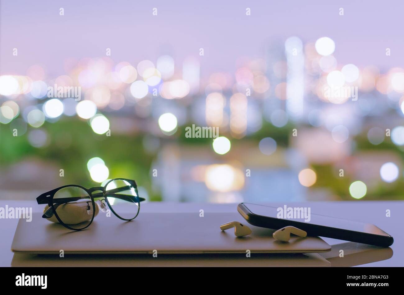 Laptop, Smartphone und Kopfhörer werden ausgeschaltet auf den Tisch mit bunten Stadt Bokeh Lichter für digitale Entgiftung, soziale Trennung, Gadget sucht Co Stockfoto
