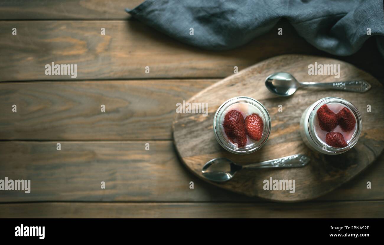 Zwei Gläser Joghurt auf einem Holzständer Stockfoto