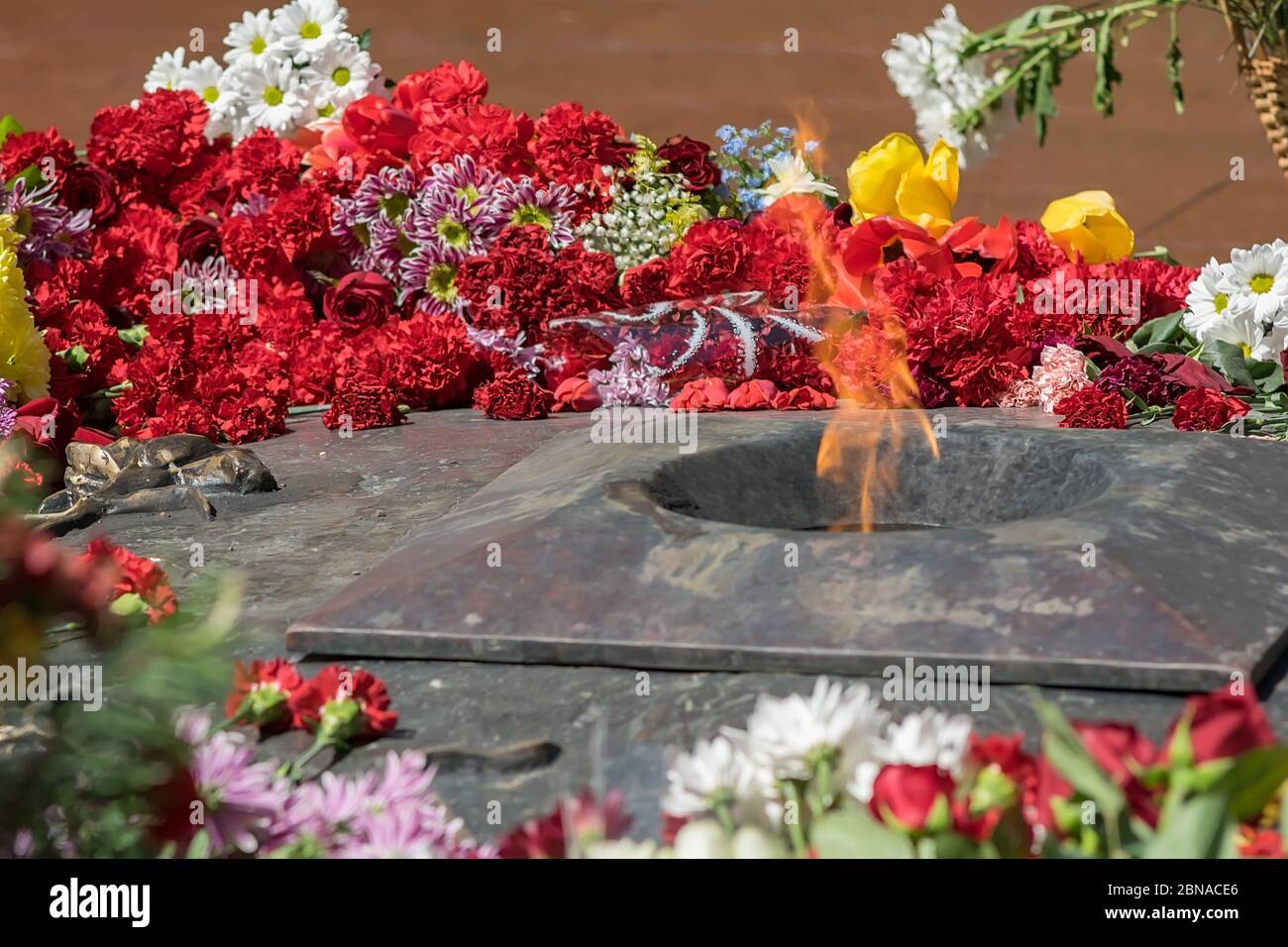Blumen liegen an der ewigen Flamme am Denkmal für die Opfer und gefallenen Soldaten Stockfoto