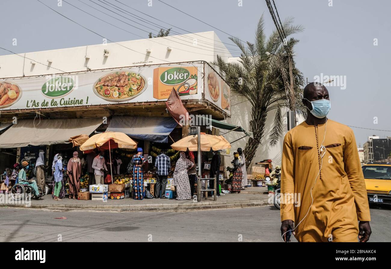 Dakar, Senegal. Mai 2020. Ein Mann mit Gesichtsmaske überquert eine Straße in Dakar, Senegal, 12. Mai 2020. Senegal hat am Mittwoch 110 neue bestätigte Fälle von COVID-19 gemeldet, was die Gesamtzahl auf 2,105 im Land bringt. Kredit: Eddy Peters/Xinhua/Alamy Live News Stockfoto