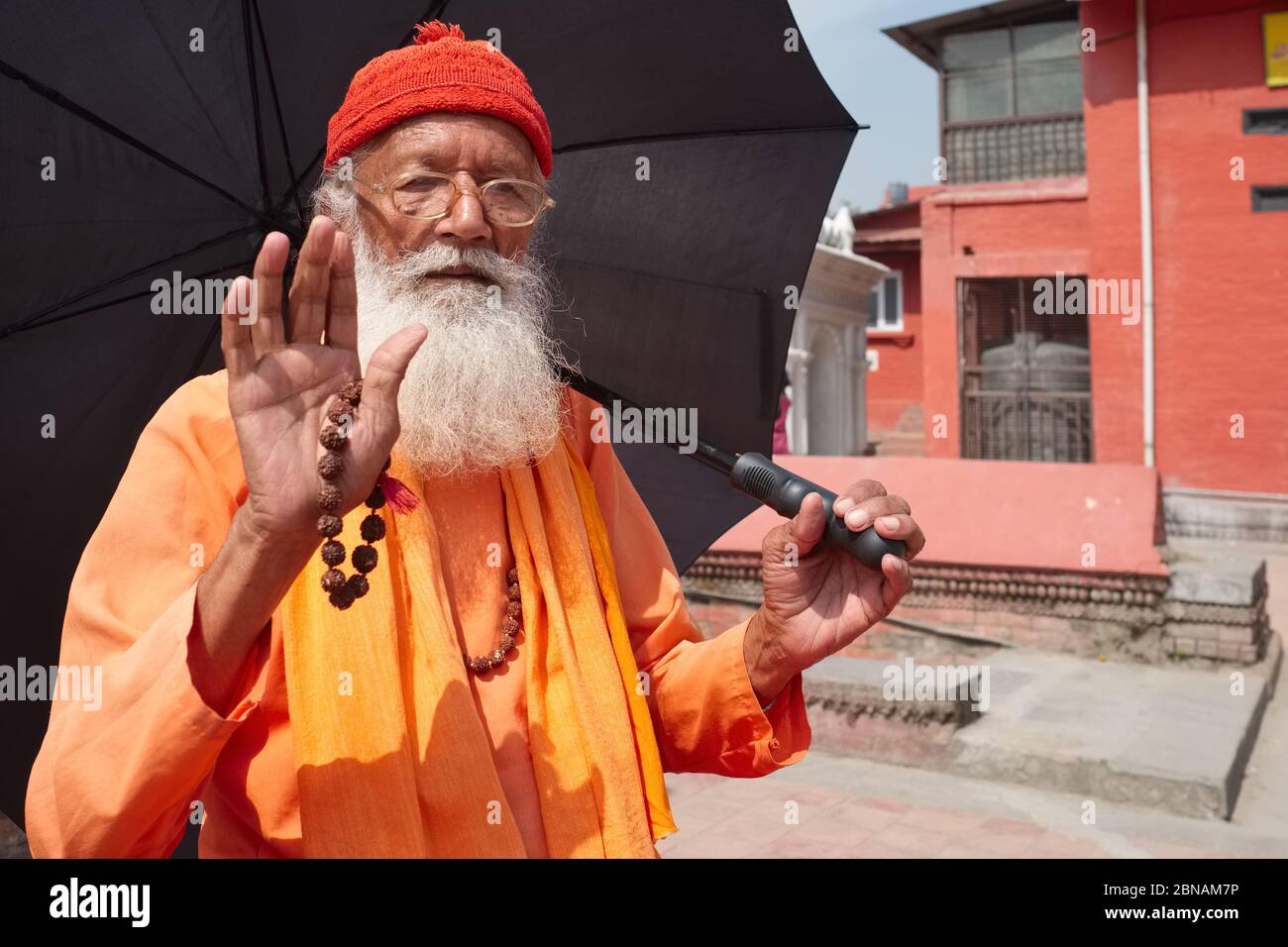 Ein Sadhu (Hindu-Heiliger), mit Schirm, der sich vor der Sonne schützt und Rudraksha-Perlen in der Hand, begrüßt den Fotografen Kathmandu Nepal Stockfoto