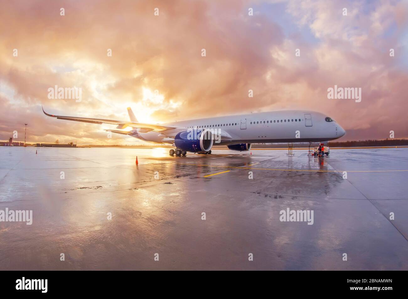 Passagierflugzeug für den gewerblichen Großraumbereich, das mit einer nassen Schürze am Flughafen während des Abendregnet bei Sonnenuntergang mit schönem Himmel geparkt wird Stockfoto