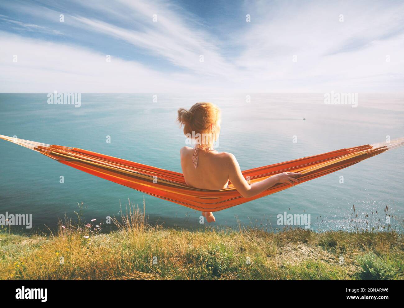 Frau, die in der Hängematte entspannt und auf das Meer starrt. Stockfoto