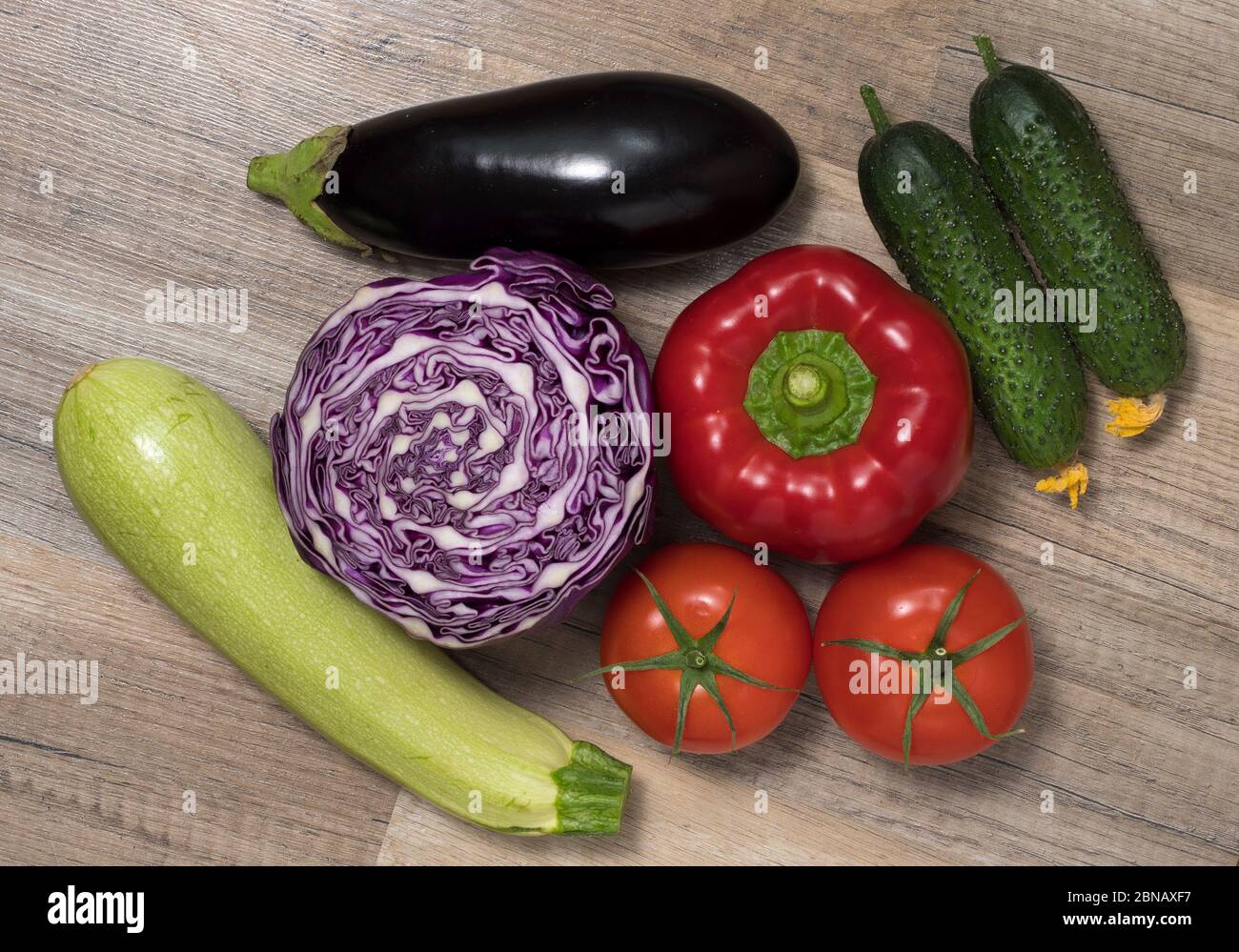 Verschiedene Gemüse (Zucchini, Gurken, Auberginen, Tomaten, Kohl) zusammen auf Holztisch gelegt. Draufsicht. Gemüsehintergrund. Stockfoto