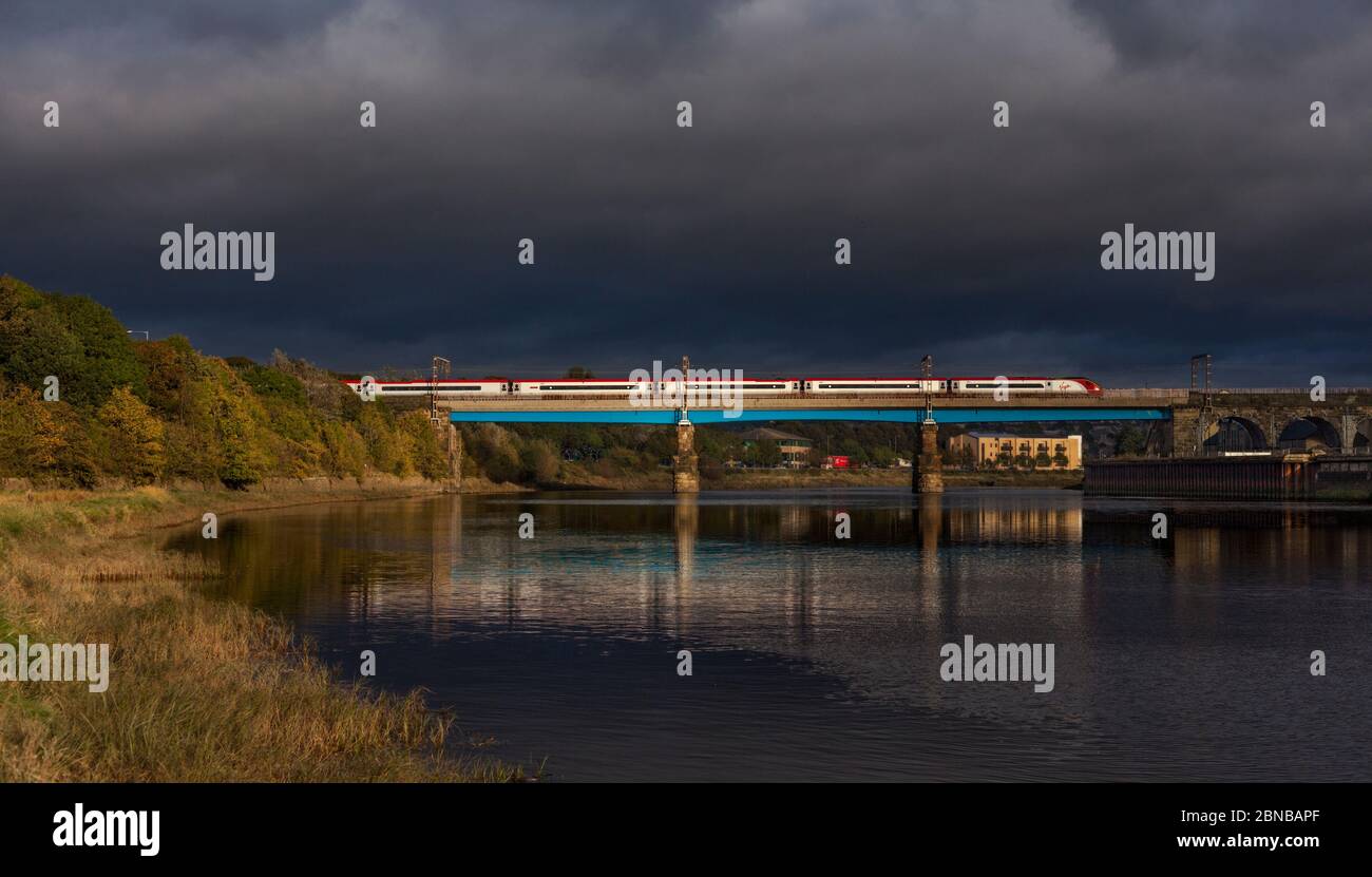 Virgin Trains Alstom pendolino Zug überquert den Fluss lune Viadukt auf der Westküste Hauptlinie bei Lancaster mit schwarzen stürmischen Wolken am Himmel Stockfoto