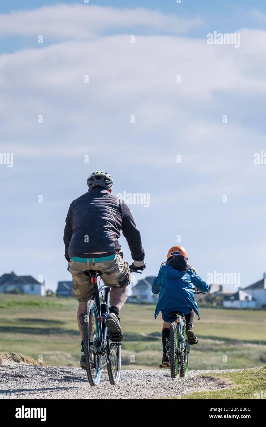 Ein Vater und ein Kind radeln gemeinsam auf einem Weg in Newquay in Cornwall. Stockfoto