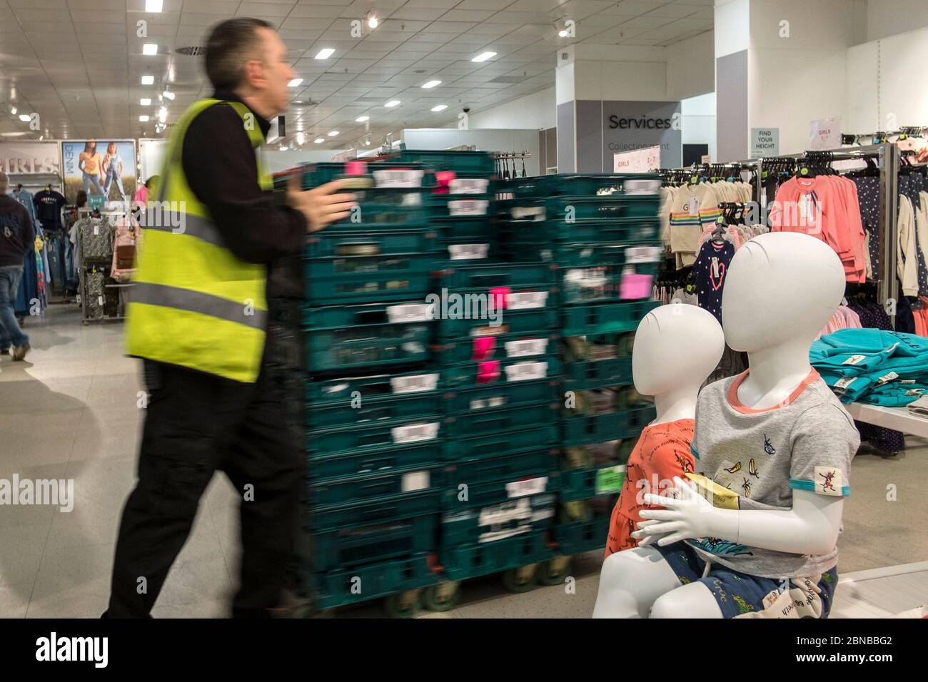 Ein Mitarbeiter, der Plastikschalen mit Waren an Schaufensterpuppen in einem Marks and Spencer Geschäft, M&S, im Truro Stadtzentrum in Cornwall vorbeischiebt. Stockfoto