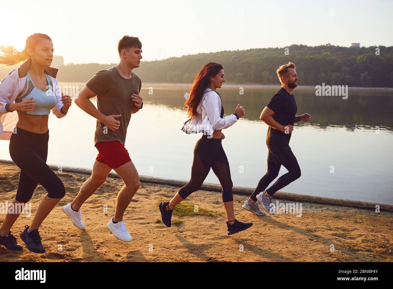 Eine Gruppe junger Sportler läuft in einem Park am See. Stockfoto