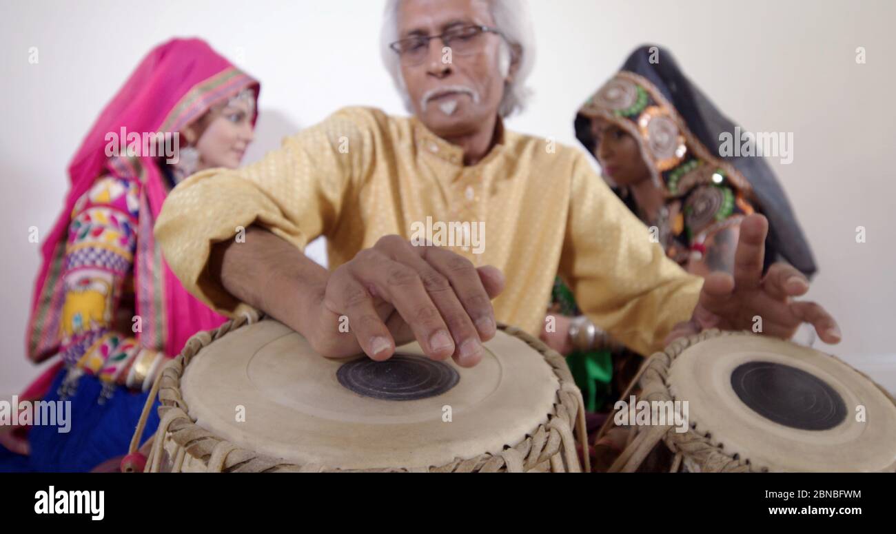 Mann spielt indische Trommeln mit Tänzerinnen. Stockfoto