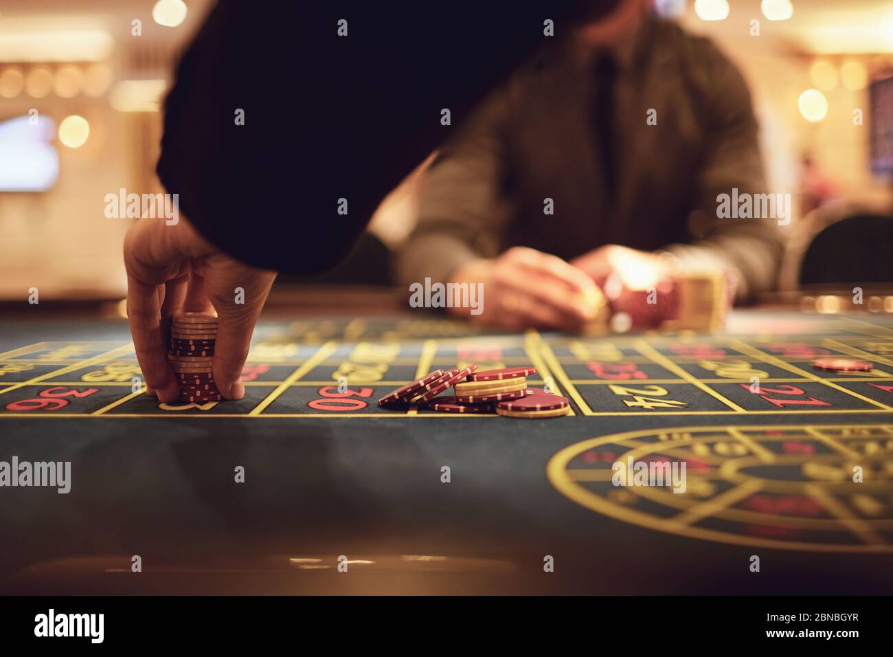 Ein Spieler spielt Roulette in einem Casino. Close-up Hand mit Chips auf dem Roulettetisch. Gambling Casino Spiel Konzept. Stockfoto