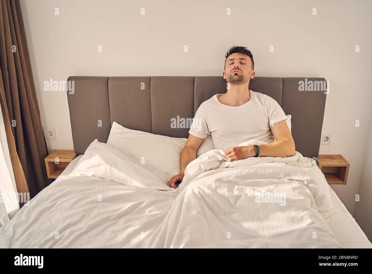 Müde Brünette Mann versucht, in seinem Bett zu schlafen Stockfoto