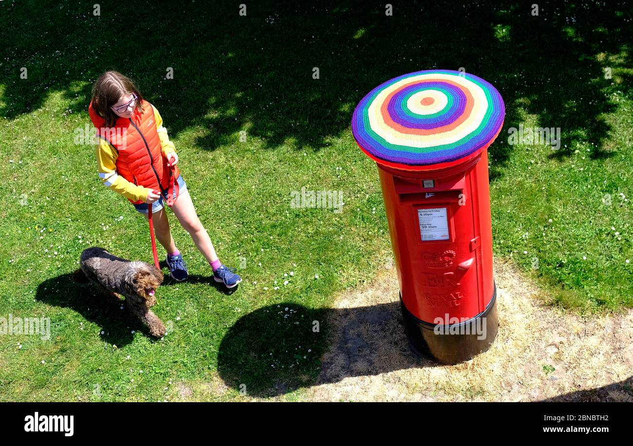 Loughborough, Leicestershire, Großbritannien. Mai 2020. Ein Mädchen geht mit ihrem Hund an einer Royal Mail Briefbox vorbei, die in Regenbogenfarben bombardiert wurde, um die Unterstützung für Schlüsselarbeiter während der Sperrung der Coronavirus-Pandemie zu zeigen. Credit Darren Staples/Alamy Live News. Stockfoto