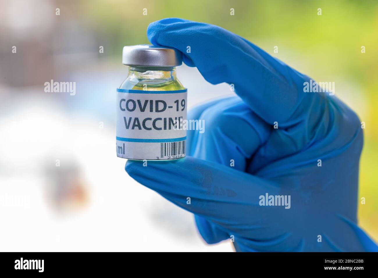Hand mit medizinischen Handschuhen in Nahaufnahme mit einer Impfflasche, die für die Medikation und Behandlung von Covid-19-Patienten verwendet wird Stockfoto