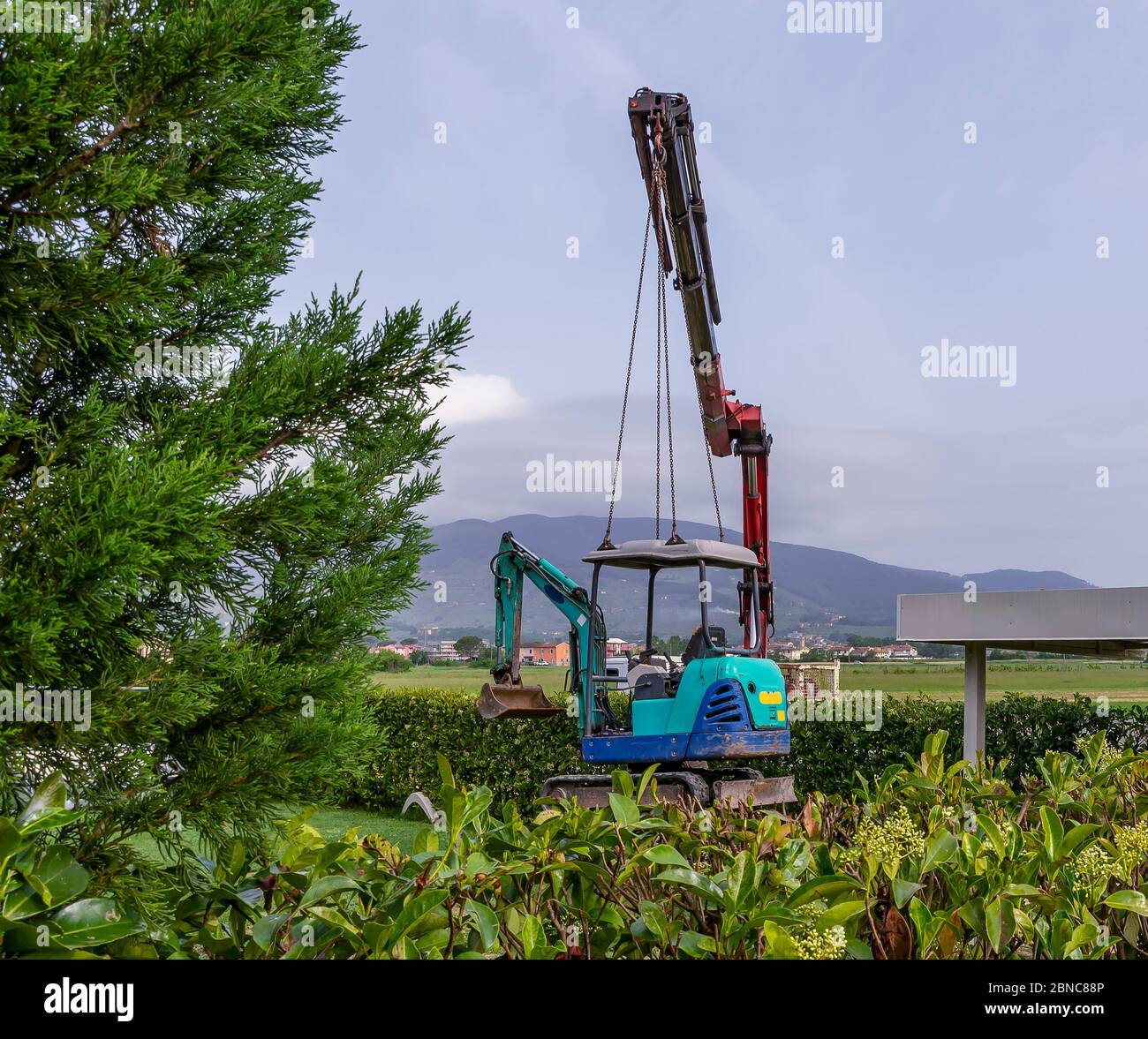 Ein Minibagger wird in die Luft gehoben, um auf einem Kranwagen transportiert zu werden Stockfoto