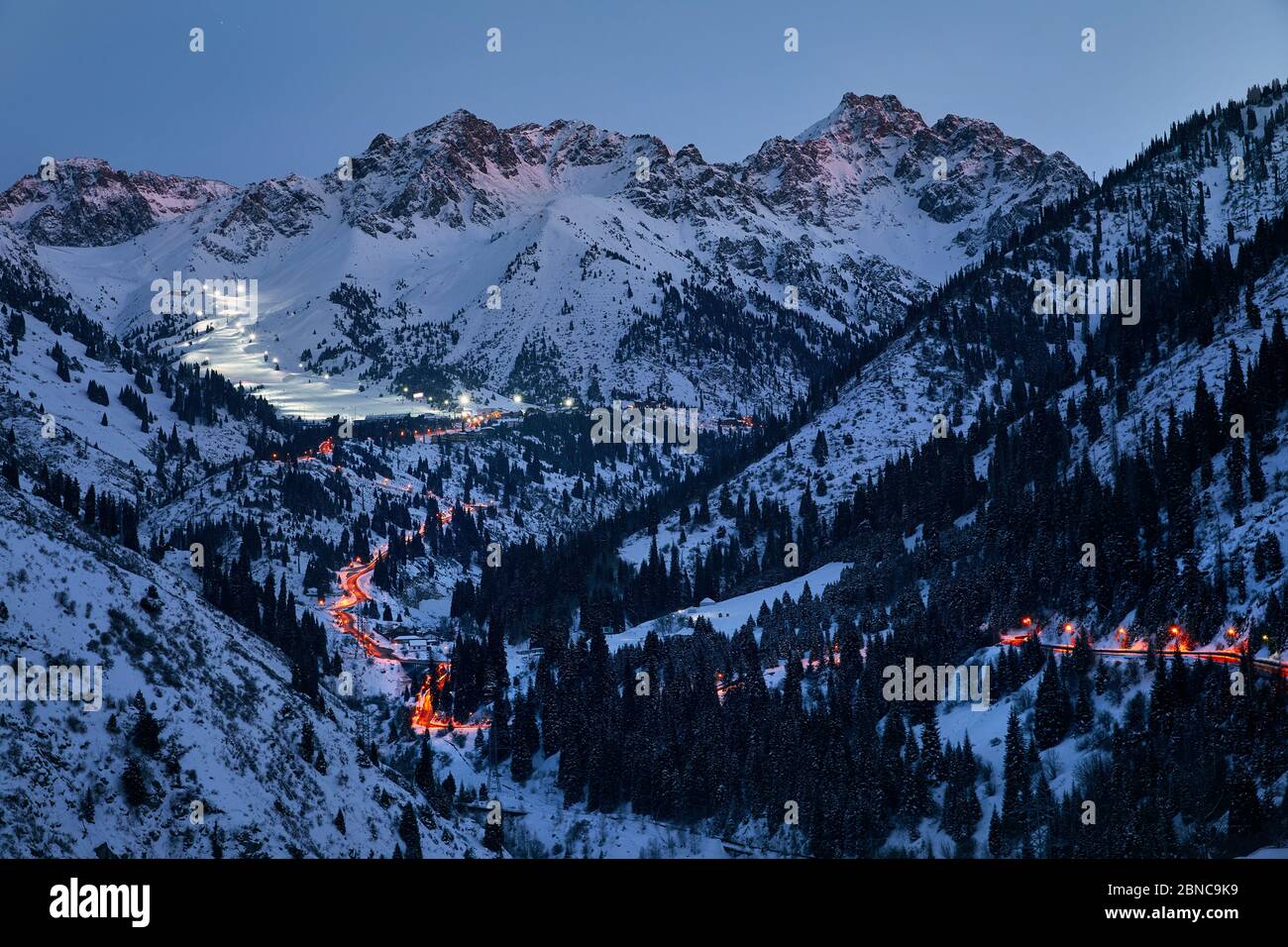 Landschaft der glühenden Straße von Medeu Eiskate zum Skigebiet Shymbulak am Tian Shan Mountains am Abend in Almaty, Kasachstan Stockfoto