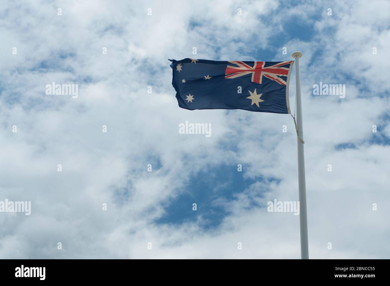 Australische Flagge winkt im starken Wind, gegen einen wolkigen blauen Himmel Stockfoto
