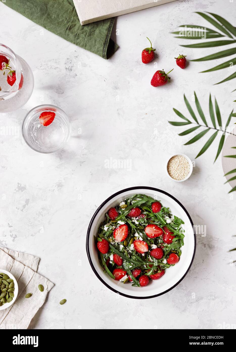 Sommersalat aus frischen Erdbeeren, Fettakäse, Rucola, Kürbis und Sesam auf weißem Hintergrund flach gelegt. Stockfoto