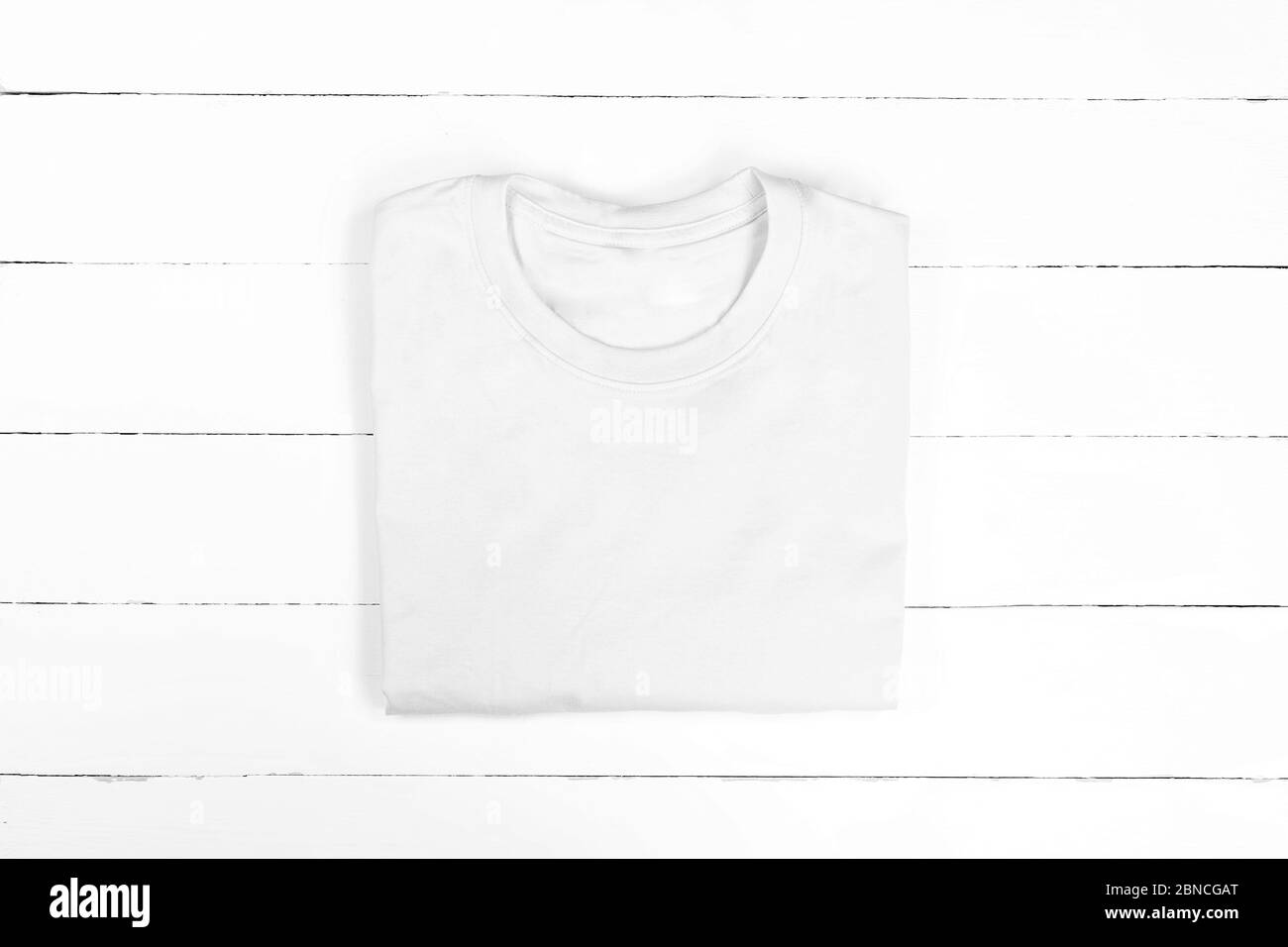 Weißes gefaltetes T-Shirt auf weißem Holzhintergrund. Flaches Lay Stockfoto